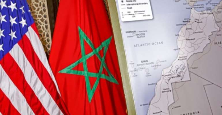 A photograph taken on December 12, 2020 shows US and Moroccan flags next to a US State Department authorised map recognising the contested territory of Western Sahara as part of Morocco. By - (AFP/File)