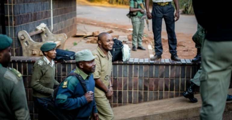 A supporter of the Movement for Democratic Change (MDC) opposition party is escorted to a prison truck outside the magistrate's court in Harare on August 6, 2018 after 27 were arrested over alleged links to post-election violence. By Zinyange AUNTONY (AFP)