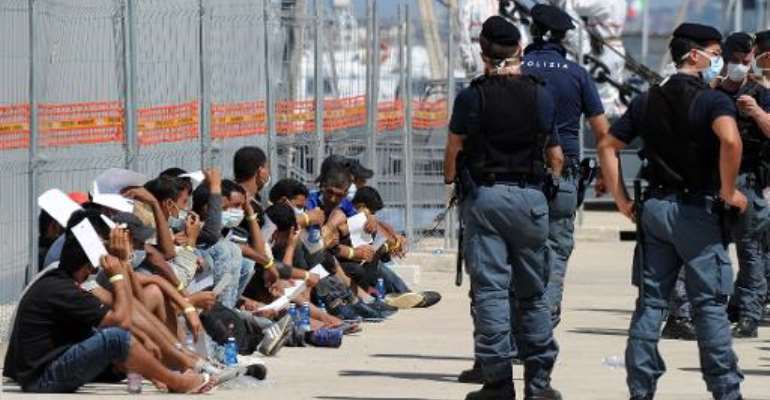Immigrants wait after disembarking from an Italian military ship on August 11, 2014 in the port of Reggio Calabria, southern Italy, following Mare Nostrum rescue operations at sea. By Giovanni Isolino (AFP/File)