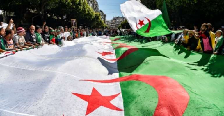 Algerian protesters march with a giant national flag during a demonstration in the capital Algiers on May 31, 2019. By RYAD KRAMDI (AFP/File)