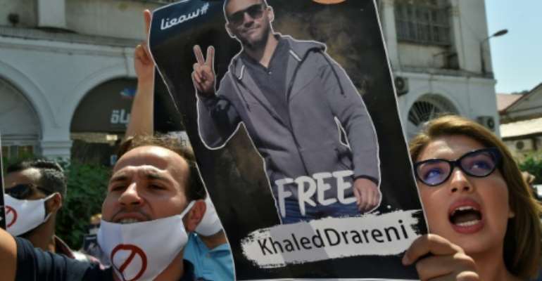 Algerians brandish a picture of journalist Khaled Drareni during a rally to protest his three-year jail term handed down after being convicted in August of charges of 'inciting an unarmed gathering'. By RYAD KRAMDI (AFP)