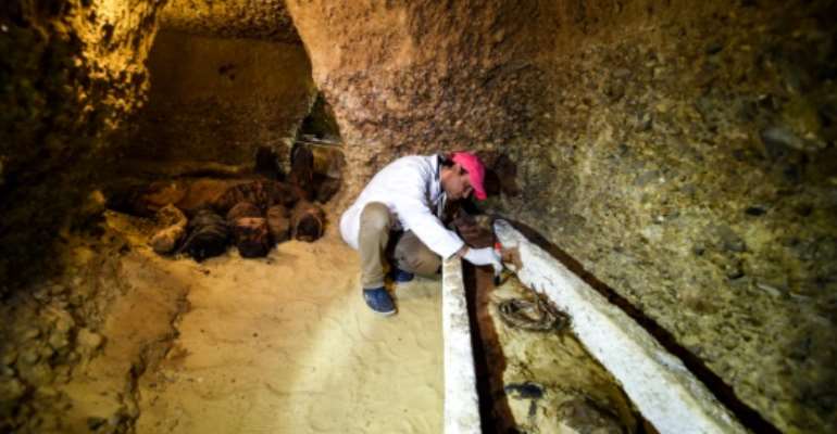 An archaeologist brushes a newly-discovered mummy laid inside a sarcophagus, part of a collection found in burial chambers dating to the Ptolemaic era (323-30 BC) in February 2019. By MOHAMED EL-SHAHED (AFP/File)