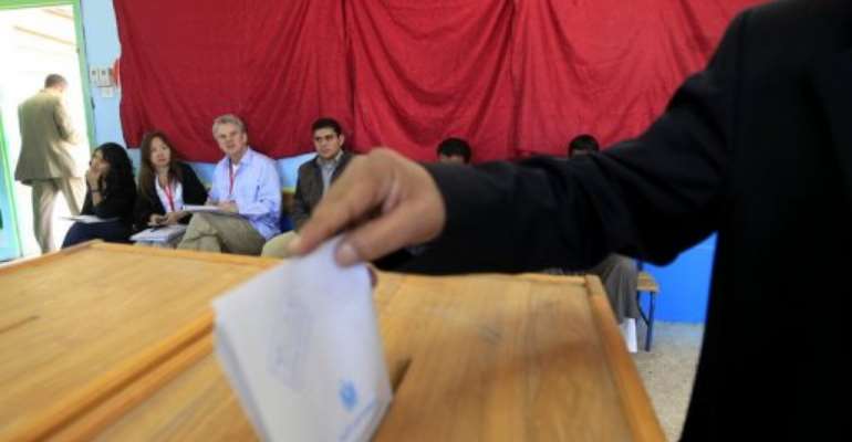 Foreign election monitors watch as an Egyptian casts his ballot at a polling station in Sharm el-Sheikh. By Mohammed Abed (AFP/File)