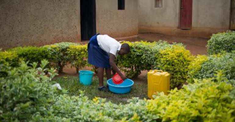 Sofia, 19 year-old daughter of a rape victim, washes utensils outside her home on the outskirts of Kigali, Rwanda on March 14, 2014. By Phil Moore (AFP)