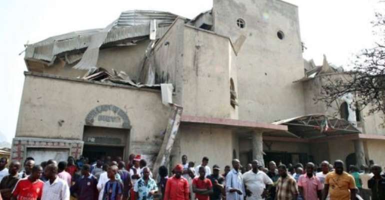 People stand in front of the partially destroyed St Theresa Catholic Church in the Madala Zuba district in Abuja. By Sunday Aghaeze (AFP)