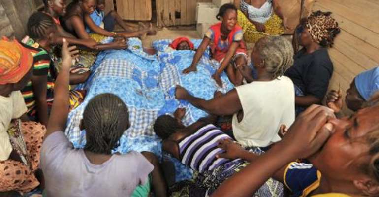 Members of a family sit on February 9, 2014 in Bangui, over the bodies of two relatives killed in one the of the city's central neighbourhoods. By Issouf Sanogo (AFP)