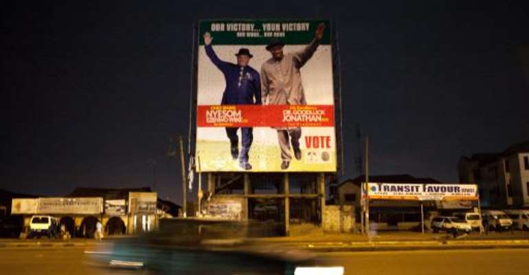 A car passes in street of Part Harcourt, Nigeria, on March 30, 2015, in front of a campaign billboard of incumbent President Goodluck Jonathan. By (AFP)