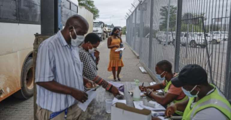 Commuters get COVID-19 test results checked at the South African side of the border -- but a surge in cases is overwhelming authorities on both sides. By Guillem Sartorio (AFP)