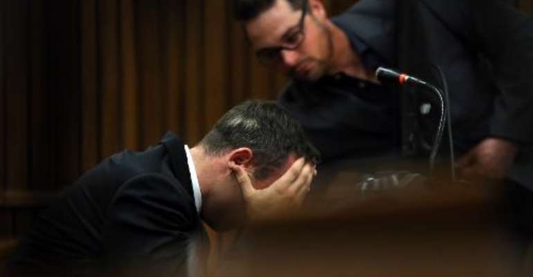 South African Paralympic track star Oscar Pistorius, flanked by his brother Carl (R), attends his trial in Court in Pretoria on April 7, 2014. By Themba Hadebe (Pool/AFP)
