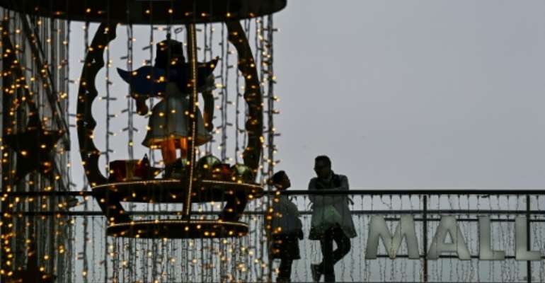 Customers stand on a balcony next to Christmas decorations in a shopping mall in Berlin. Germany plans to ease virus curbs for Christmas. By Tobias SCHWARZ (AFP)