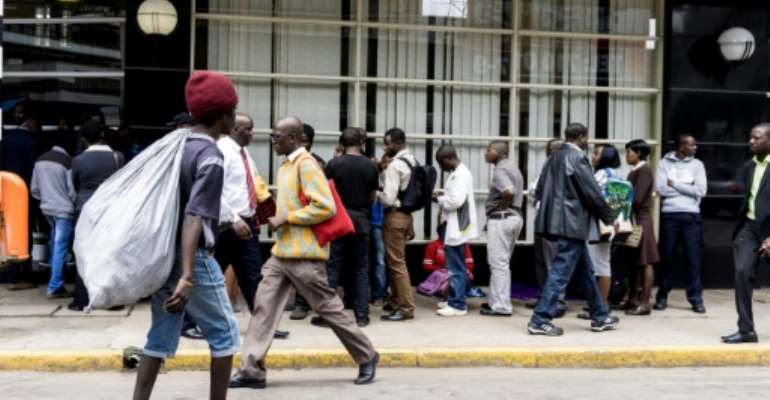 Due to Zimbabwe's crippling cash shortage, banks limit withdrawals meaning that long queues of people waiting outside are a common sight. By ZINYANGE AUNTONY (AFP/File)
