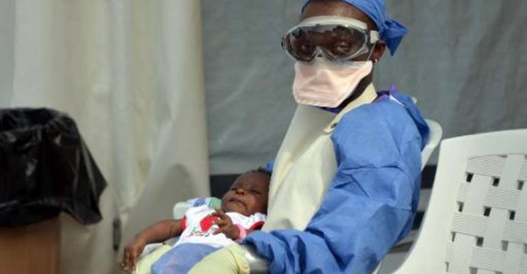 A Liberian health worker holds a baby infected with the Ebola virus at the NGO Medecins Sans Frontieres (Doctors Without Borders) Ebola treatment center in Monrovia on October 18, 2014. By Zoom Dosso (AFP/File)