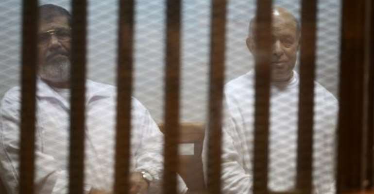Egypt's deposed president Mohamed Morsi (left) and his former chief of staff Refaa al-Tahtawi sit inside the defendants' cage during their 2014 trial in Cairo. By Ahmed Ramadan (AFP/File)