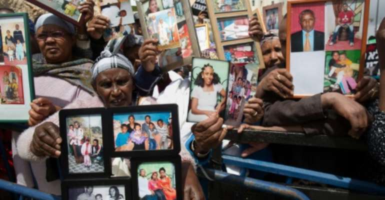 Israelis from the Ethiopian community hold up photographs of their relatives in front of Israel's Prime Minister's office in Jerusalem on March 20, 2016. By Menahem Kahana (AFP)