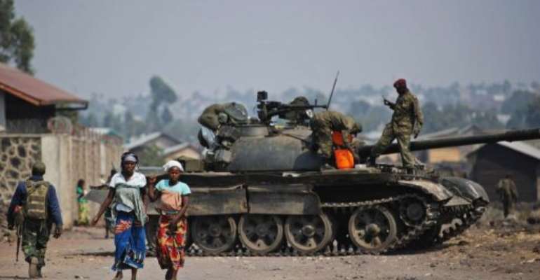 Two Congolese women walk past a government army tank in Munigi, on the outskirts of Goma on July 15, 2013. By Phil Moore (AFP/File)