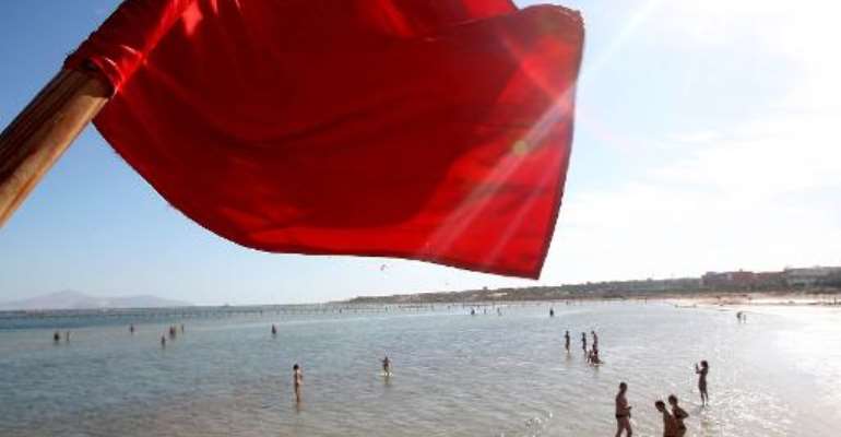 A red flag serving as a warning of shark sightings flutters over tourists on the beach in the Red Sea resort of Sharm el-Sheikh on December 8, 2010. By (AFP/File)