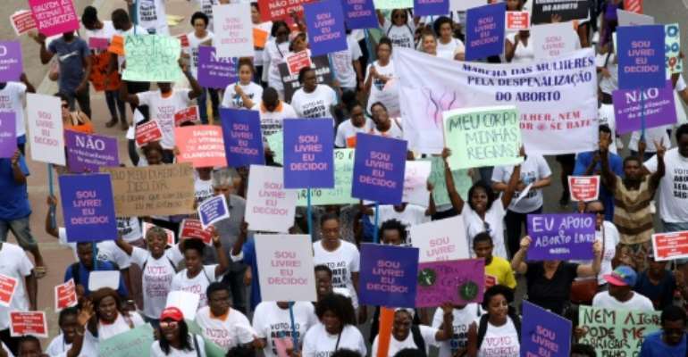 Hundreds of Angolans hold placards and shout slogans as they march to protest against a draft law that would criminalise all abortions. By AMPE ROGERIO (AFP)