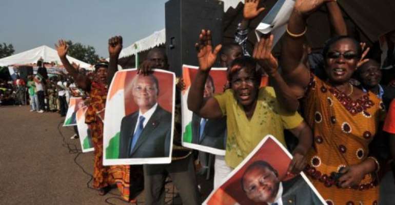 Supporters of Ivorian President Alassane Ouattara hold posters portraying him upon his arrival on April 22, in Guiglo. By Sia Kambou (AFP/File)