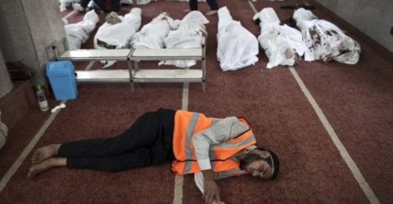 An Egyptian volunteer sleeps on the carpet of a mosque in Cairo where lines of bodies were laid out on August 15, 2013. By Mahmoud Khaled (AFP)