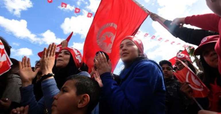 Tunisians wave their national flag and chant slogans during a march against extremism outside Tunis' Bardo Museum on March 29, 2015. By Fethi Belaid (AFP)