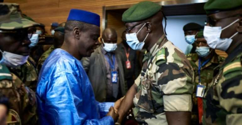Junta number two Malick Diaw, right, shakes hands with Issa Kaou Djim, a leading figure in the June 5 Movement as talks began. By MICHELE CATTANI (AFP)