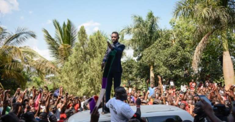 Kyagulanyi addressed cheering supporters outside his home as the police looked on. By Isaac Kasamani (AFP)