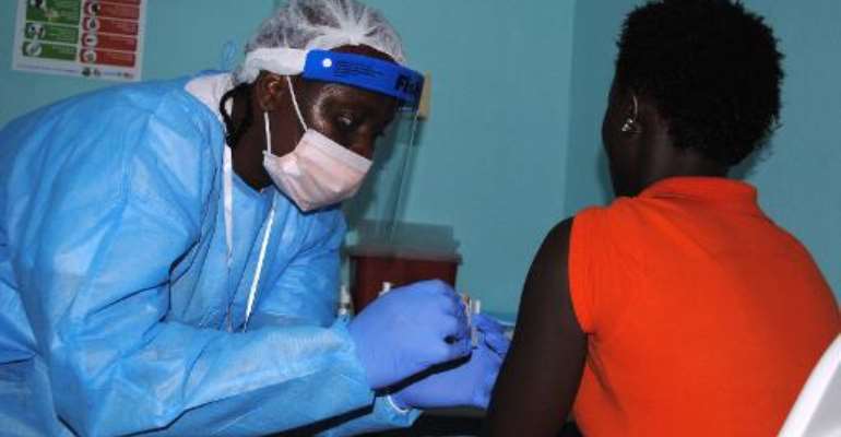 An adhesive bandage is placed on the arm of a volunteer after she was administered an experimental Ebola vaccine at Redemption Hospital in New Kru Town, a suburb of Monrovia, on February 2, 2015. By Zoom Dosso (AFP/File)
