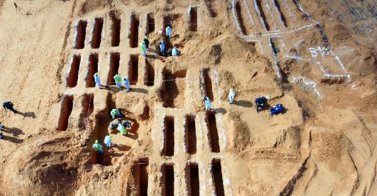 Libyan members of the team excavating mass graves investigate remains in Tarhuna, where 17 bodies have been discovered. By Mahmud TURKIA (AFP)