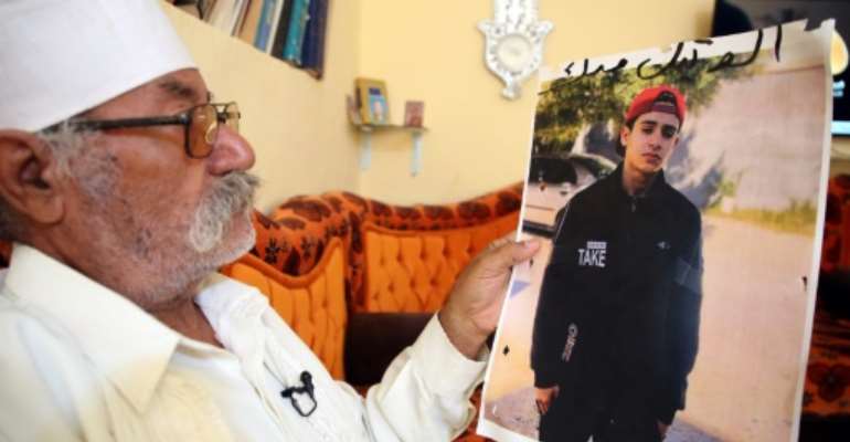Libyan Mohamed al-Magri holds a picture of his 20-year-old missing son Haitham who he believes was killed and buried in a mass grave in the western city of Tarhuna after armed men took him from his home a year ago. By Mahmud TURKIA (AFP)