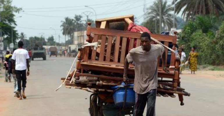 A man pulls a cart full of pieces of furnitures he looted as he walks near a convoy of French soldiers on February 9, 2014 in Bangui. By Issouf Sanogo (AFP)