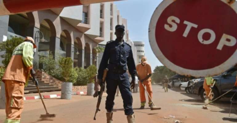 A Malian police officer stands guard as municipal workers clean outside the Radisson Blu hotel in Bamako on November 22, 2015, two days after a deadly Jihadist attack. By Issouf Sanogo (AFP/File)
