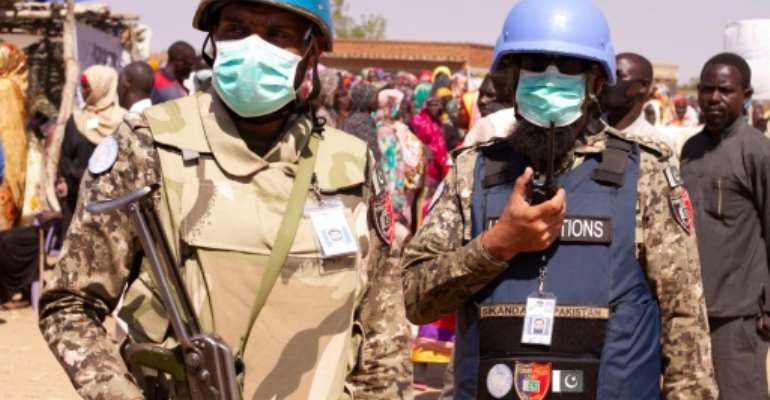 Members of the United Nations and African Union peacekeeping mission (UNAMID) look on as Sudanese internally displaced people stage a sit in to protest against the end of their mandate, in Kalma camp in Nyala, in late December. By - (AFP)
