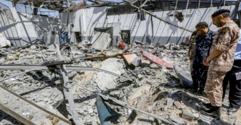 Military officers of the Libyan Government of National Accord (GNA)inspect damage at a migrant detention center in the capital Tripoli's southern suburb of Tajoura on July 3, 2019, following an air strike on a nearby building that left dozens killed. By Mahmud TURKIA (AFP)