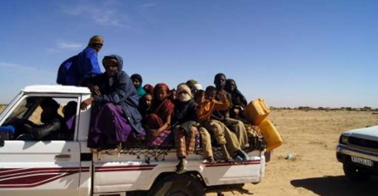 Malian refugees ride in the back of a truck transporting them on a dirt road from Timbuktu to the Mauritanian town of Fassala on January 18, 2013. By - (Al-Akhbar News Agency/AFP/File)