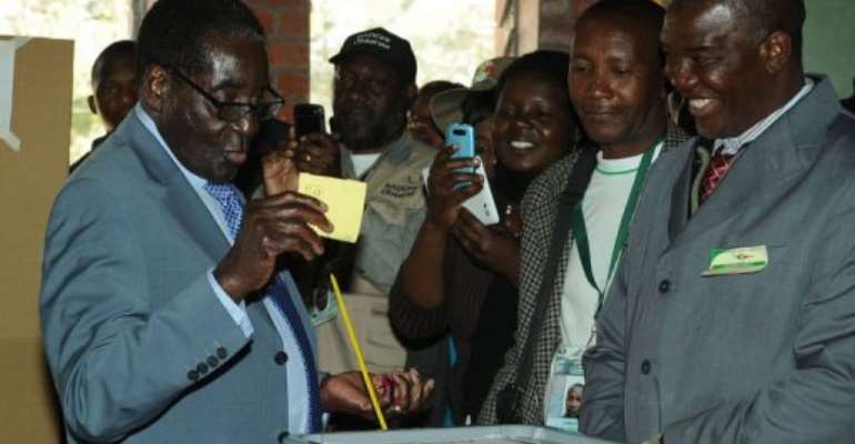 Zimbabwe President Robert Mugabe (L) casts his vote at a polling booth in a school in Harare on July 31, 2013. By Alexander Joe (AFP)