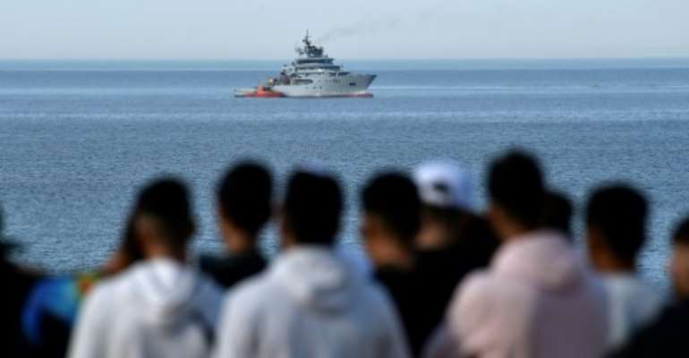 People watch as a naval ship arrives at the scene of a helicopter crash in the Mediterranean Sea off the coast of Algeria on Wednesday. By Ryad KRAMDI (AFP)
