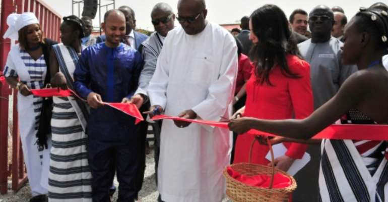 President of Burkina Faso Roch Marc Christian Kabore (C) cuts the ribbon during the inauguration of a new movie theatre which runs on solar power in Ouagadougou on February 24, 2017. By Ahmed OUOBA (AFP)