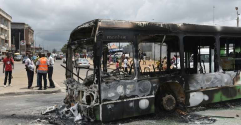 Protesters torched a bus in a working-class district of Abidjan. By SIA KAMBOU (AFP)