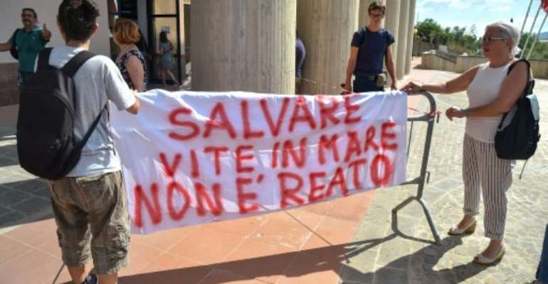 Rackete's supporters hold a banner reading 'Saving lives at sea is not a crime' outside the courthouse. By Andreas SOLARO (AFP)