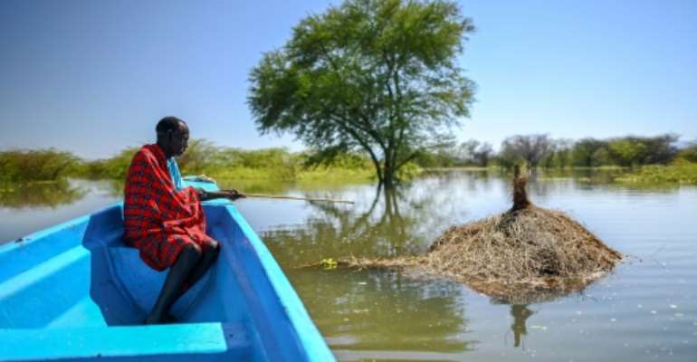 Richard Lichan Lekuterer, 60, sits in a boat as it glides above what used to be his homestead. By TONY KARUMBA (AFP)