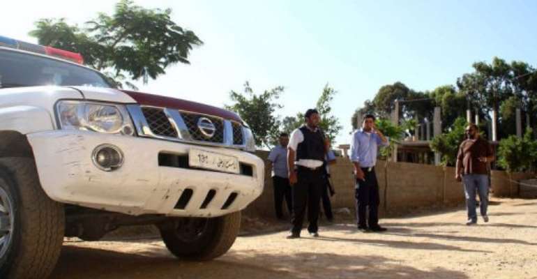 Libyan security members gather outside after a British diplomatic convoy car was hit by a grenade in Benghazi. By (AFP)