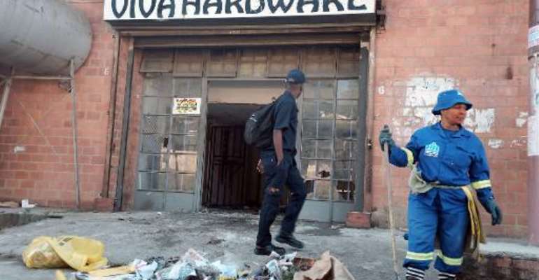 A worker from the eThekwini municipality cleans up after a xenophobic attack on a Somali businesses in Umlazi township, south of Durban, on April 10, 2015. By Rajesh Jantilal (AFP)