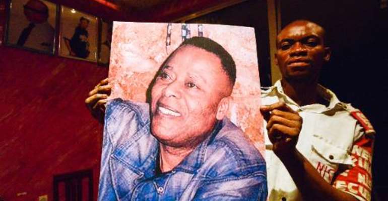 A man holds a picture of late Congolese singer King Kester Emeneya in the bar