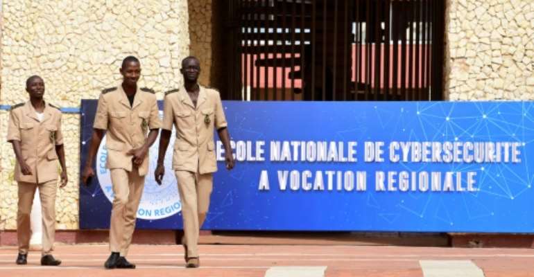 Students of the National School of Administration walk near the banner announcing the creation of a National School of Cybersecurity in Dakar on November 6, 2018. By SEYLLOU (AFP)