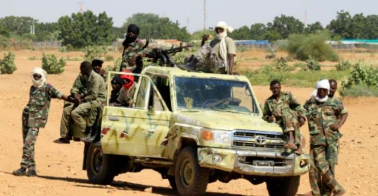 Sudanese troops stand guard on the side of the road in the village of Tabit, North Darfur, on November 20, 2014. By Ashraf Shazly (AFP/File)