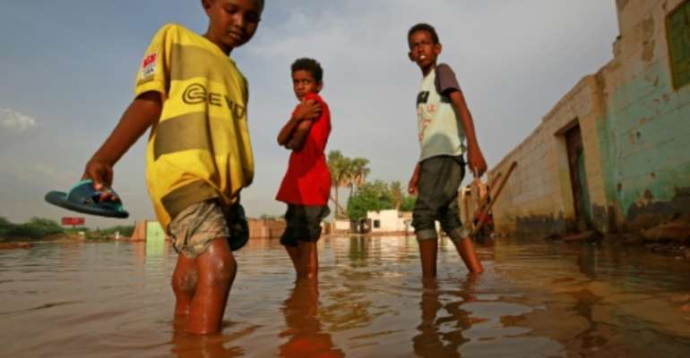Sudanese boys make their way through a flooded street in the capital's twin city of Omdurman. By ASHRAF SHAZLY (AFP)