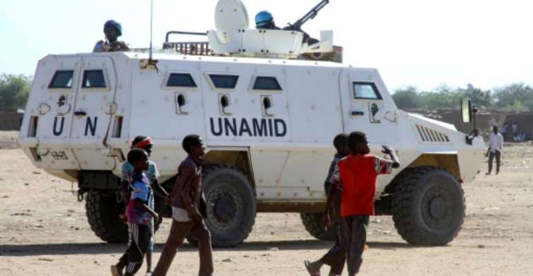 Sudanese children walk past an armoured vehicle of the United Nations and African Union peacekeeping mission (UNAMID) in Kalma Camp for internally displaced people in Nyala, the capital of South Darfur, on Wednesday. By - (AFP)