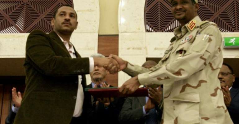 Sudanese deputy chief of the ruling miliary council Mohamed Hamdan Dagalo and protest movement Alliance for Freedom and Changes leader Ahmad al-Rabiah shake hands after inking a power-sharing agreement. By Ebrahim HAMID (AFP)