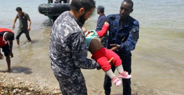 The body of a baby who died in a shipwreck off the coast of Libya is carried ashore in al-Hmidiya, east of the capital Tripoli on June 29, 2018. By Mahmud TURKIA (AFP)