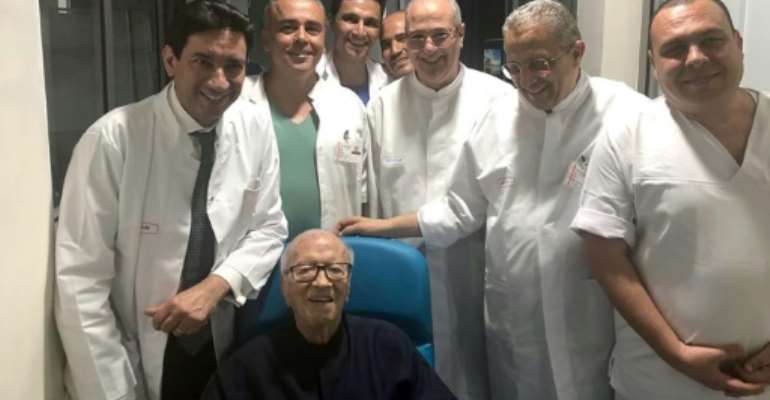 Tunisian President Beji Caid Essebsi smiles as he leaves hospital surrounded by his doctors. By - (Tunisian Presidency/AFP)